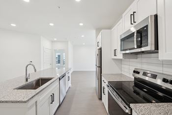 A modern kitchen with white cabinets and stainless steel appliances.